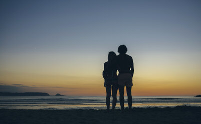 Junges Paar beobachtet den Sonnenuntergang am Strand - DAPF00689
