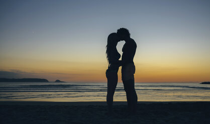 Junges Paar küsst sich in der Abenddämmerung am Strand - DAPF00690