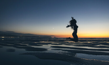 Young woman jumping by the sea at sunset - DAPF00695