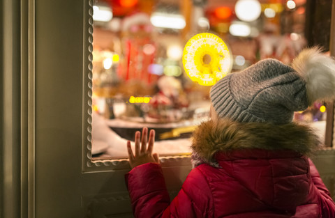 Mädchen schaut in ein Weihnachtsschaufenster, lizenzfreies Stockfoto