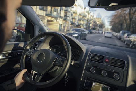 Lenkrad und Hand eines Mannes, der ein Auto durch die Stadt fährt, lizenzfreies Stockfoto