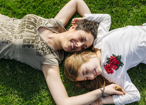 Mother and daughter having fun lying in the grass stock photo