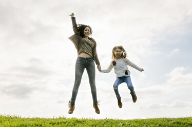 Happy mother and daughter jumping on a meadow - MGOF03225