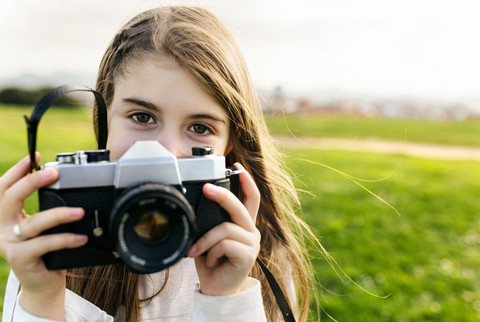 Portrait of a girl holding an old-fashioned camera outdoors stock photo