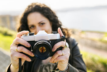 Portrait of a woman holding an old-fashioned camera outdoors - MGOF03231