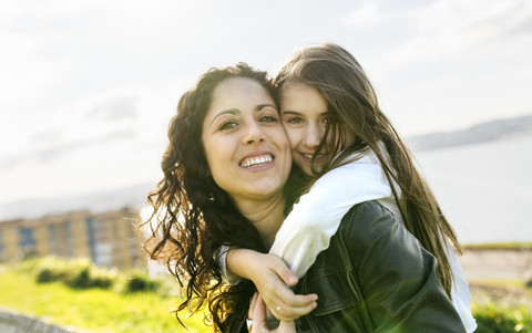 Portrait of happy mother carrying daughter outdoors stock photo