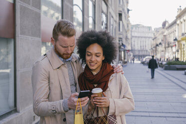 Couple in the city with cell phone and shopping bags - MOMF00150