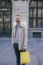 Porträt eines lächelnden Mannes mit Einkaufstasche - MOMF00159