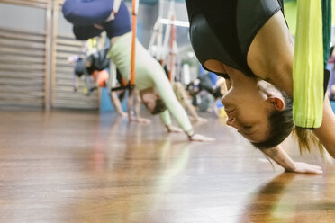 Eine Gruppe von Frauen bei einer Aerial-Yoga-Stunde - MGOF03240