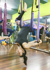 Frau übt Aerial Yoga im Unterricht - MGOF03249