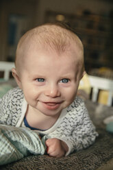Glückliches drei Monate altes Baby, das aufschaut und etwas in seinem Kinderbettchen anlächelt - MFF03476