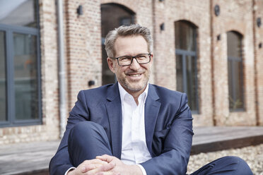 Portrait of relaxed businessman wearing blue suit and glasses - FMKF03862