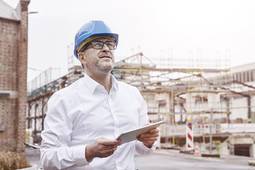 Portrait of smiling man with tablet wearing blue hart hat - FMKF03866