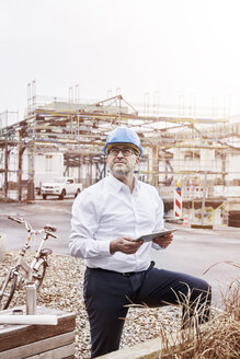 Portrait of man with tablet wearing hart hat at construction site - FMKF03867