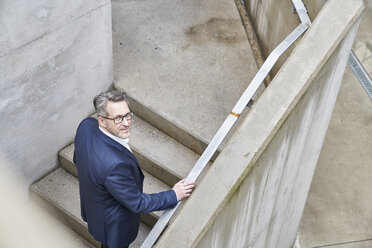 Portrait of businessman standing on stairs - FMKF03904