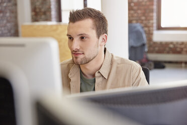 Young man sitting in office using computer - RHF01871