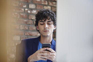 Young man working in office, reading smartphone message - RHF01894