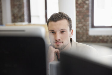 Young man sitting in office using computer - RHF01917