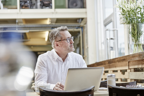Mature businessman in cafe using laptop stock photo
