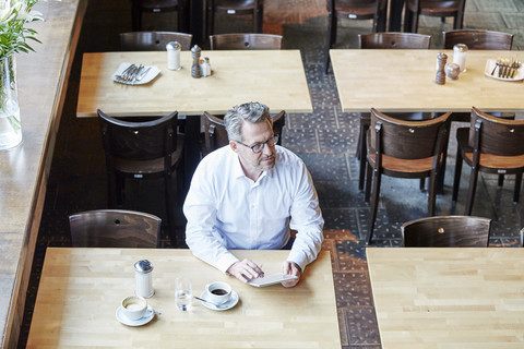 Reifer Geschäftsmann im Café mit Tablet, lizenzfreies Stockfoto