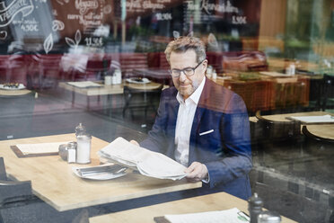 Älterer Geschäftsmann im Café, der Zeitung liest - FMKF03938