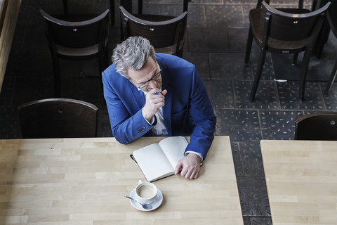 Reifer Geschäftsmann in Café schreibt in Tagebuch, lizenzfreies Stockfoto