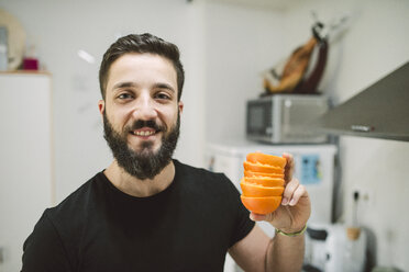 Smiling man holding orange peels - RAEF01827