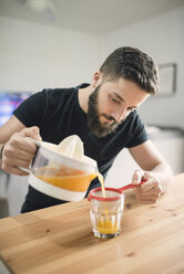 Junger Mann macht frischen Orangensaft - RAEF01828