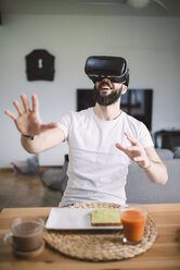 Man having breakfast wearing virtual reality glasses - RAEF01840