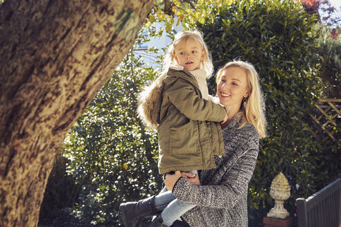 Happy mother carrying daughter in garden - KDF00719