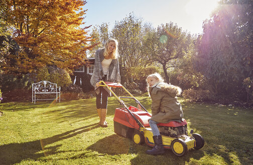 Mother with daughter in garden lawnmowing - KDF00721