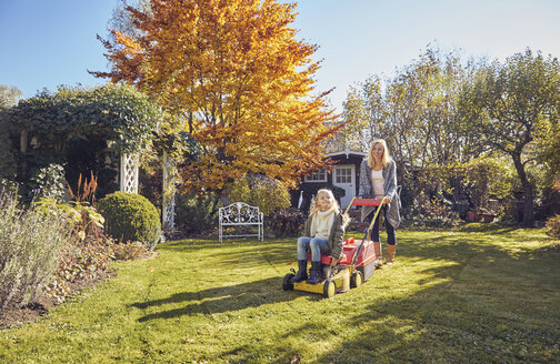 Mother with daughter in garden lawnmowing - KDF00722