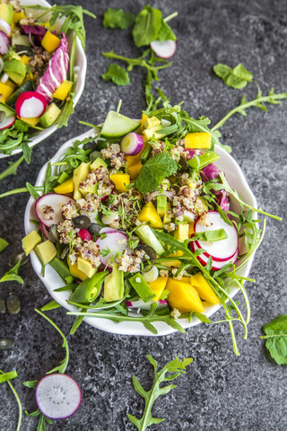 Mango quinoa salad with rocket, avocado, cucumber, red radishes and pumpkin seeds stock photo