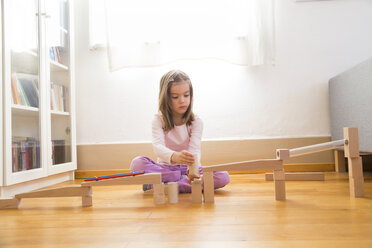 Kleines Mädchen hockt auf dem Boden und baut eine Murmelbahn mit Bauklötzen - LVF06053