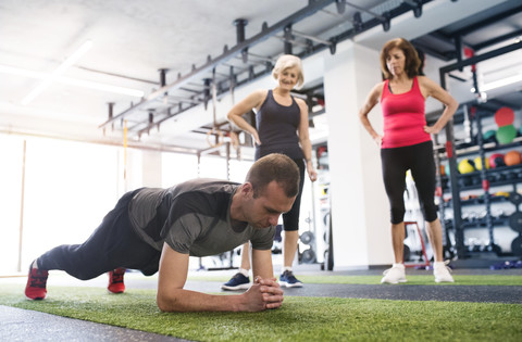 Two senior women watching personal trainer in gym stock photo