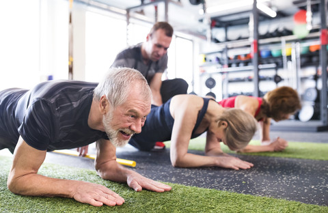 Gruppe von fitten Senioren mit Personal Trainer im Fitnessstudio, lizenzfreies Stockfoto