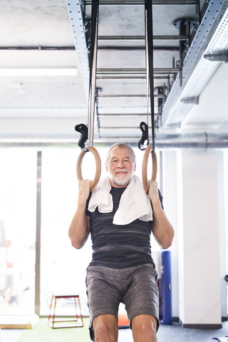 Fitter älterer Mann im Fitnessstudio, der an Ringen trainiert, lizenzfreies Stockfoto