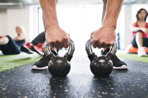 Nahaufnahme eines Mannes beim Training mit Kettlebells im Fitnessstudio - HAPF01473