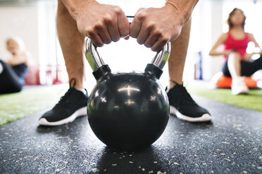 Nahaufnahme eines Mannes, der mit einer Kettlebell im Fitnessstudio trainiert - HAPF01474