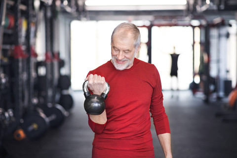 Älterer Mann beim Training mit der Kettlebell im Fitnessstudio, lizenzfreies Stockfoto