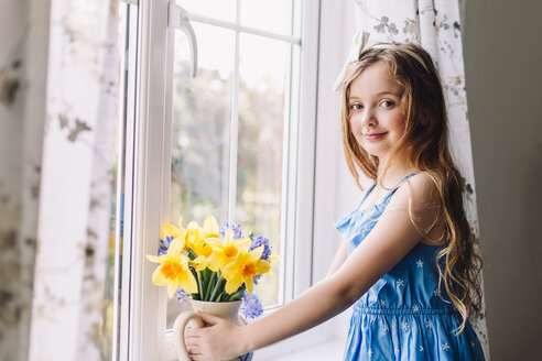 Porträt eines lächelnden Mädchens mit Blumenvase mit Narzissen und Hyazinthen zu Hause - NMSF00043