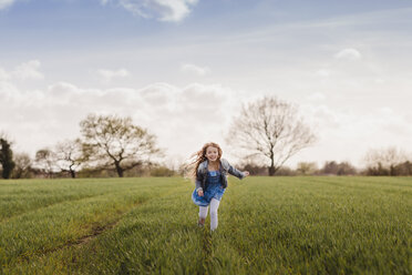 Smiling girl running on a field - NMSF00047