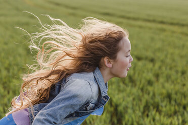 Girl with blowing hair running on a field - NMSF00049