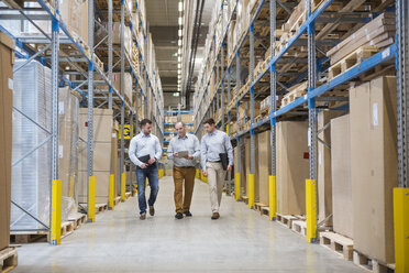 Three men walking in factory warehouse - DIGF01720