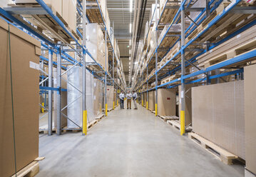 Three men standing in factory warehouse - DIGF01727