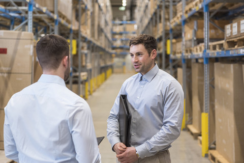 Two men talking in factory warehouse stock photo