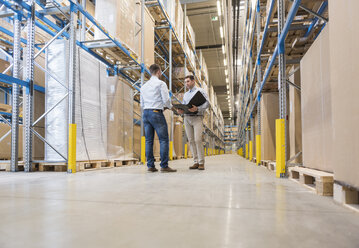 Two men with folder talking in factory warehouse - DIGF01733