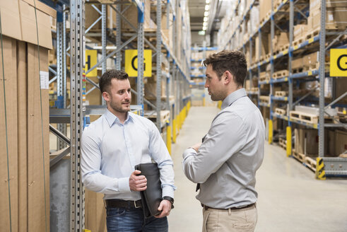 Two men talking in factory warehouse - DIGF01734