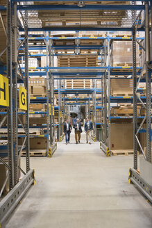 Three men walking in factory warehouse - DIGF01738