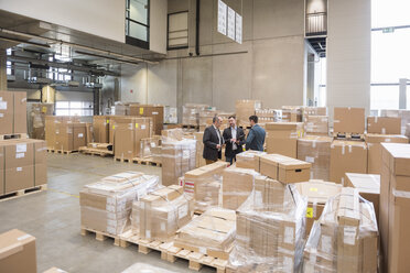 Three men in factory warehouse surrounded by cardboard boxes - DIGF01741